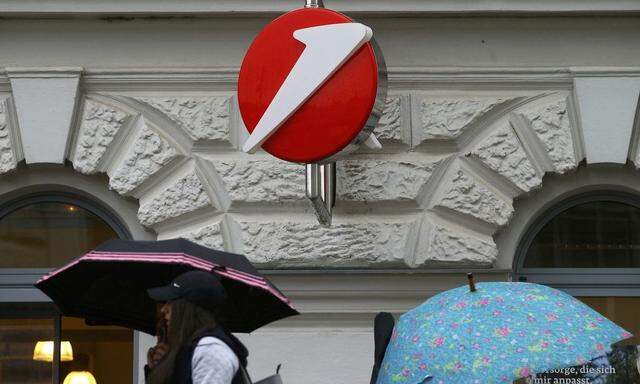 People carrying umbrellas pass a Bank Austria branch office in Vienna
