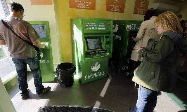 People use an automated teller machine inside a branch of Sberbank in St. Petersburg