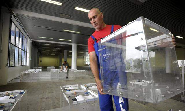 A municipal worker arranges ballot boxes to be used for a referendum, announced by the Greek government for July 5, at the northern city of Thessaloniki