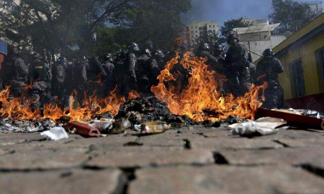 Riot policemen stand behind burning rubbish during a protest against the 2014 World Cup in Sao Paulo 