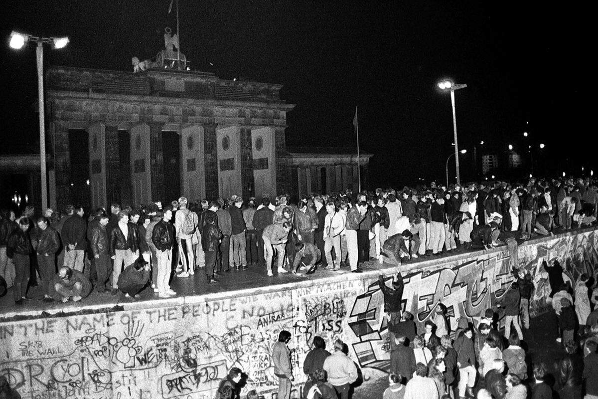 Am zugemauerten Brandenburger Tor durchbrechen tausende Menschen die Absperrungen und tanzen auf der Mauer. Erst ab 3.30 Uhr riegeln Beamte aus Ost und West den Zugang wieder ab.