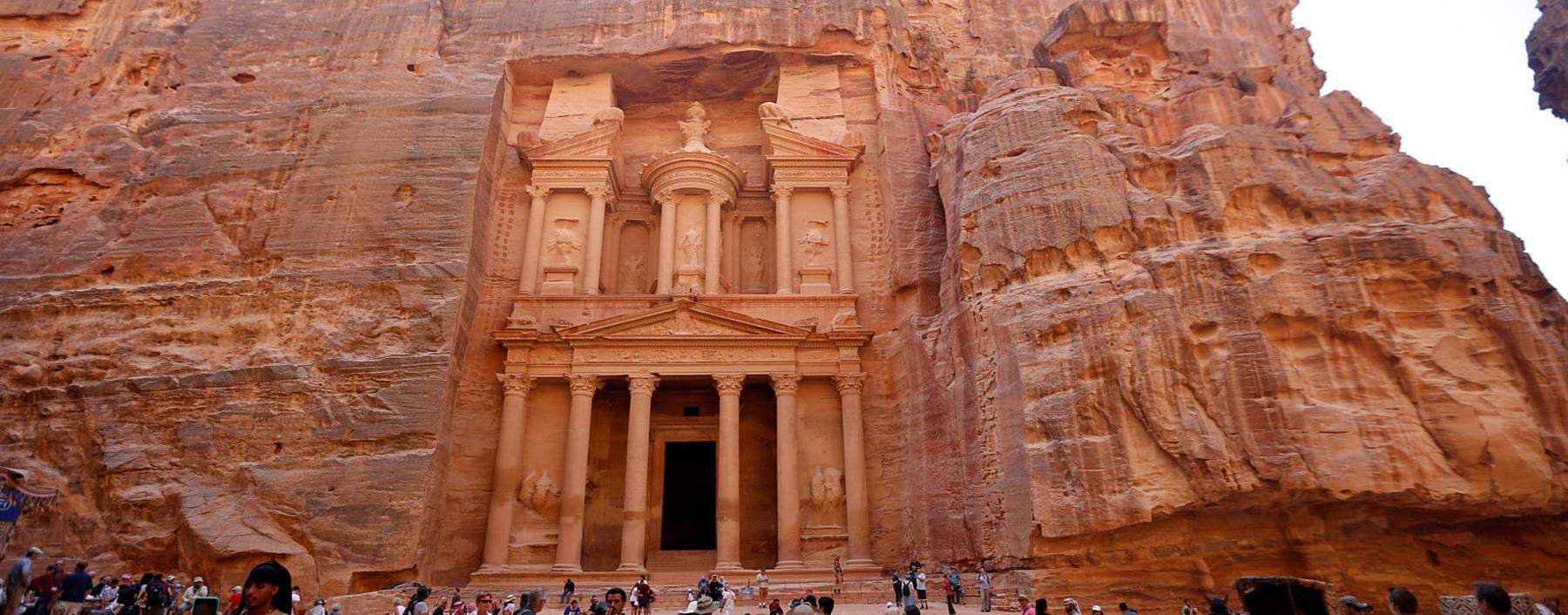 Tourists take pictures in front of the treasury site in the ancient city of Petra, south of Amman