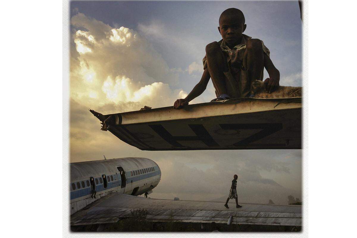 Fotoreportage von Michael Christopher Brown: Kinder spielen im Dezember 2012 auf zurückgelassenen Flugzeugen auf dem Flughafen Goma in der Demokratischen Republik Kongo. Die Flugzeuge wurden aufgrund von Kriegen und einem Vulkanausbruch im Jahr 2002 zurückgelassen. Die Kinder verkaufen umgebaute Teile der Wracks auf den Straßen von Goma.