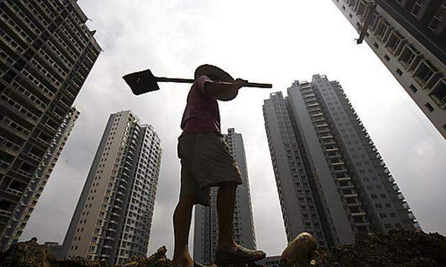 In this Monday, Aug. 16, 2010 photo, a worker walks with a shovel at a construction site in Suining, 