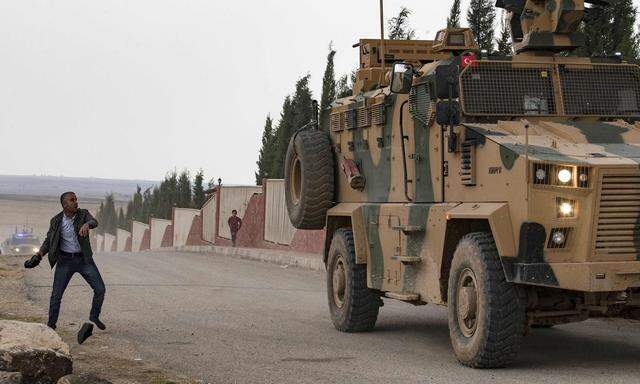 Schwieriger Syrien-Einsatz. Ein Mann bewirft ein türkisches Fahrzeug mit Schuhen. Die Türkei hat auch IS-Kämpfer eingefangen.