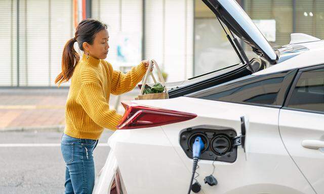 Mid adult woman loading groceries into her electric car