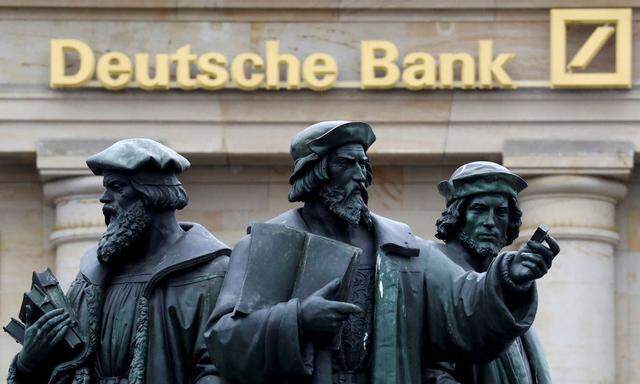 A statue is pictured next to the logo of Germany's Deutsche Bank in Frankfurt