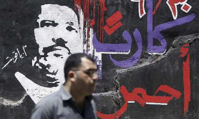A man walks past graffiti depicting Egyptian President Mohamed Mursi near Tahrir Square in Cairo