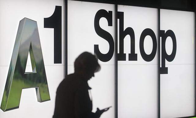 A woman holds her mobile phone as she walks past a shop of Telekom Austria brand A1 in Vienna