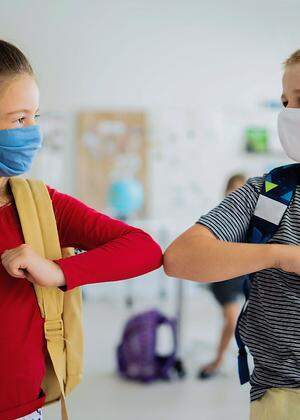 Small children with face mask back to school after coronavirus quarantine, greeting.