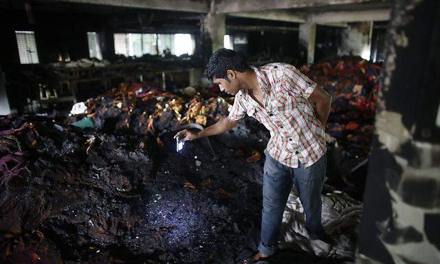 Ein Arbeiter begutachtet, was nach dem Brand noch übrig geblieben ist, bei dem in Bangladesch mindestens acht Menschen ums Leben kamen.