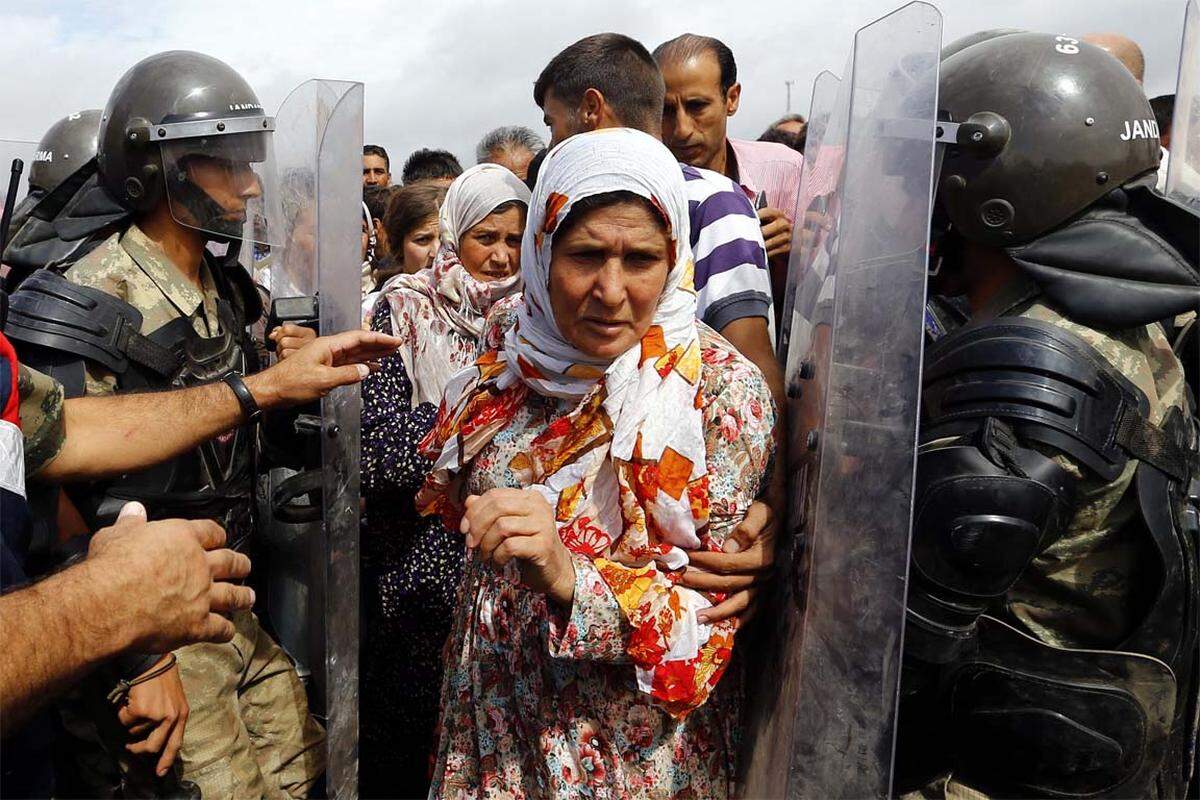 Syrische Flüchtlinge und türkische Polizei an einem Grenzübergang zwischen dem Bürgerkriegsland und der Türkei.
