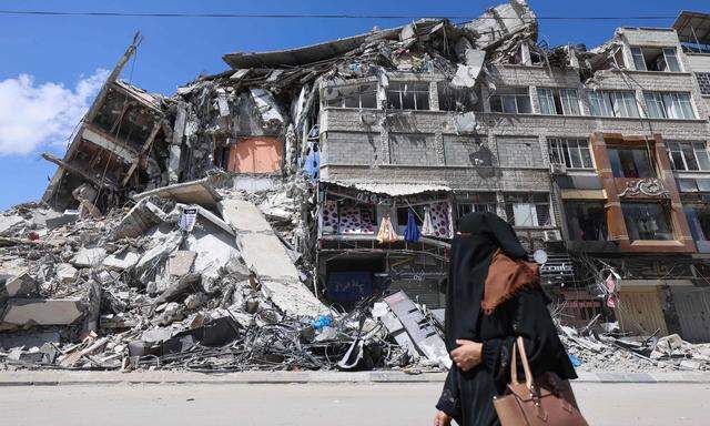 Frau vor einem zerstörten Gebäude in Gaza