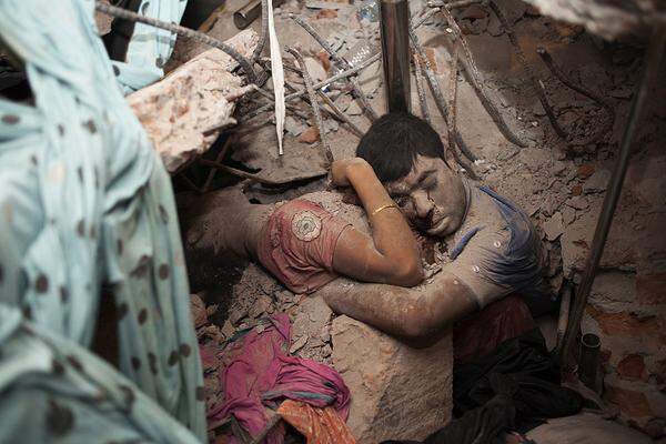 Taslima Akhter, Bangladesch Am Tag nach dem Einsturz des Rana Plaza am 24. April 2013, in Sabhar, Bangladesch, in dem fünf Textilfabriken untergebracht waren, liegen noch Opfer in den Trümmern. Mehr als 800 Menschen starben, darunter auch dieser Mann und diese Frau, die sich im Augenblick des Todes umarmten. In welchem Verhältnis diese beiden Menschen zueinander standen ist nicht bekannt.