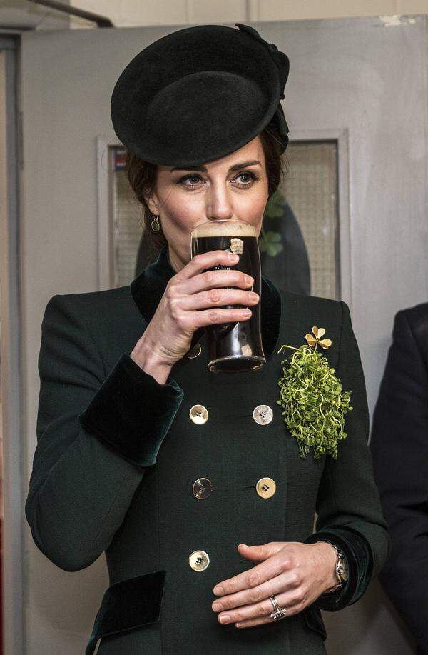 ...ein Stück, das sie wenige Stunden zuvor in Großbritannien uraufgeführt hatte: Zum St. Patrick's Day überreicht die Herzogin - mittlerweile schon fast traditioneller Weise - Klee an Soldaten, und das in Grün. Zu dem Anlass in Hounslow ergänzte Kate das Mantelkleid, ihre Gianvito-Rossi-Pumps (grün!), die Ohrringe von Monica Vinader (grün!) und ihre Handtasche (Grün! Und in Krokodillederoptik) nicht nur um eine goldene Brosche von Queen Mum, sondern auch um ein Hütchen von Lock &amp; Co. (ein alter Hut, übrigens: Sie trug es schon einmal davor, zu Weihnachten 2015).