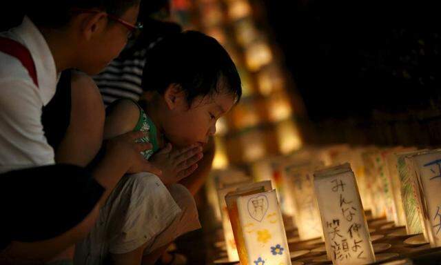 Boy prays during a candlelit memorial event to mourn the victims of the 1945 atomic bombing at Nagasaki´s Peace Park in Nagasaki