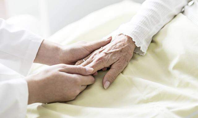 Sinnstiftende Arbeit: eine Pflegerin hält die Hand einer Seniorin.