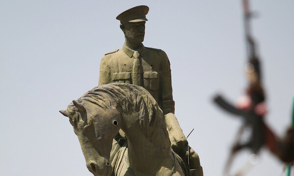 Ein kurdischer Kämpfer hält seine Waffe vor die Statue von Bassel al-Assad, dem Bruder des syrischen Präsidenten Bashar, im Ghwairan-Viertel von Hasaka, Syrien.