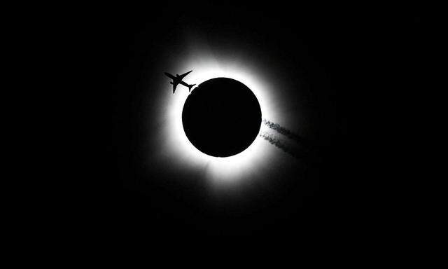 Ein Flugzeug fliegt in der Nähe der totalen Sonnenfinsternis über das Memorial Stadium in Bloomington, Indiana.