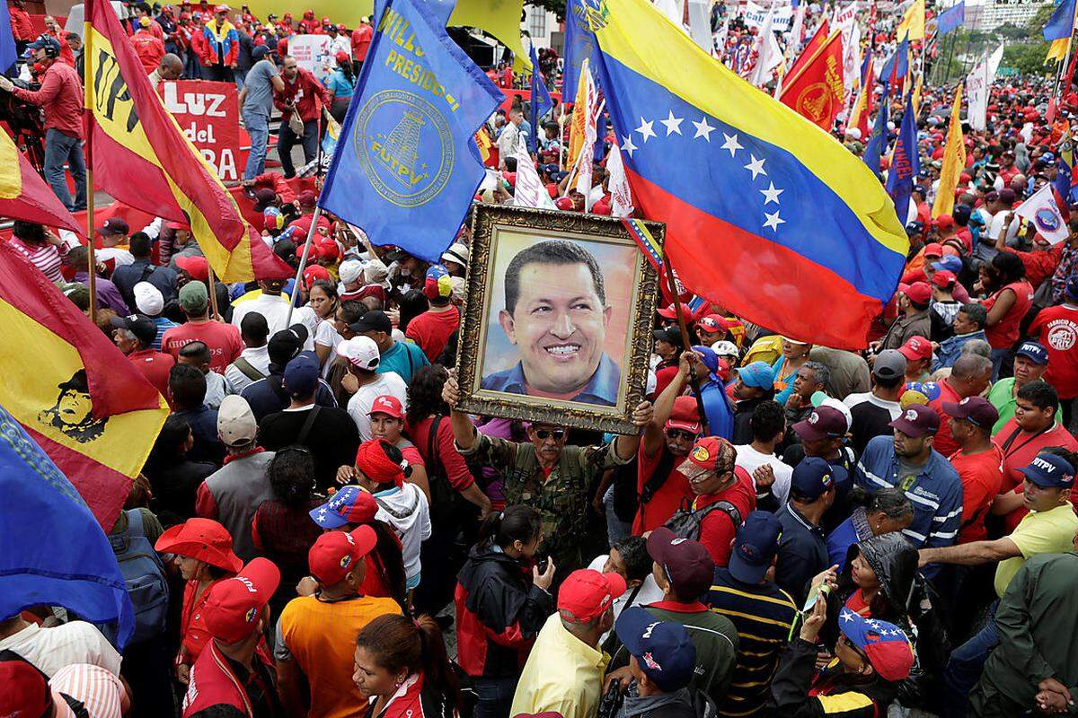 Auch in Venezuela gedachten Menschen während der Aufmärsche den Verstorbenen. Demonstranten in der Hauptstadt Caracas tragen ein Porträt des Verstorbenen Präsidenten Hugo Chavez mit sich.