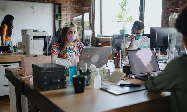 Business people working at their desks with screen partition in between them.