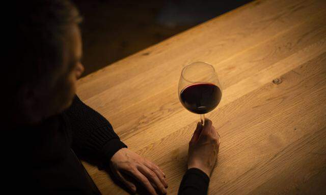 Symbolfoto zum Thema Alkoholismus: Eine Frau sitzt allein zu Hause an einem Tisch mit einem Glas Rotwein. Berlin, 23.01.