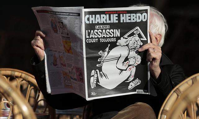 A man reads the latest edition of French weekly newspaper Charlie Hebdo with the title ´One year on, The assassin still on the run´ on a cafe terrasse in Nice