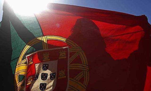 A Portugal fan holds the country's national flag during the team's World Cup soccer match against Ghana at a public screening in Lisbon
