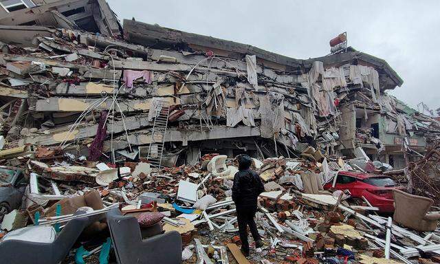 Ein Mann steht vor einem zusammengestürzten Gebäude in der türkischen Stadt Kahramanmaras.
