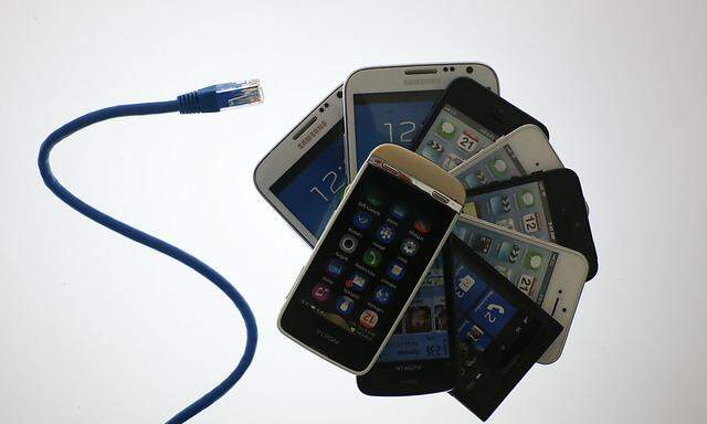 An illustration picture shows a network cable next to a pack of smartphones in Berlin
