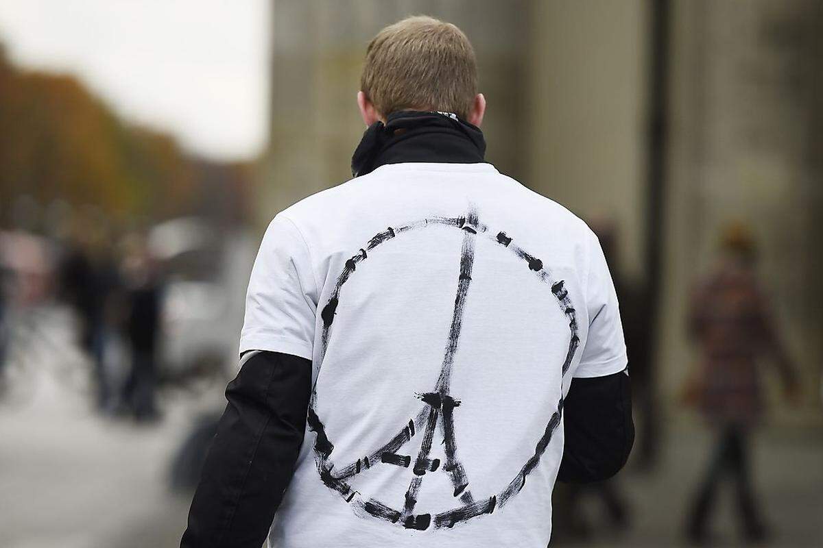 Dieser Mann geht über den Pariser Platz in Berlin. Das Friedenssymbol mit dem Eiffelturm hat er sich auf sein T-Shirt gemalt. Auf dem Platz in der deutschen Hauptstadt, direkt am Brandenburger Tor, befindet sich die französische Botschaft Deutschlands.