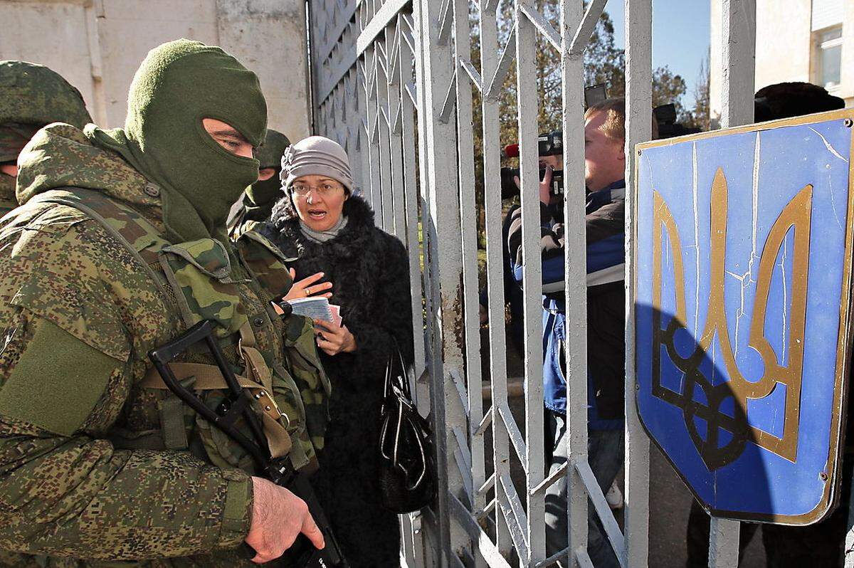 Debatten zwecklos: Eine Zivilistin redet auf einen der maskierten Soldaten außerhalb der - ebenfalls blockierten - ukrainischen Marinebasis Novoozerny ein.