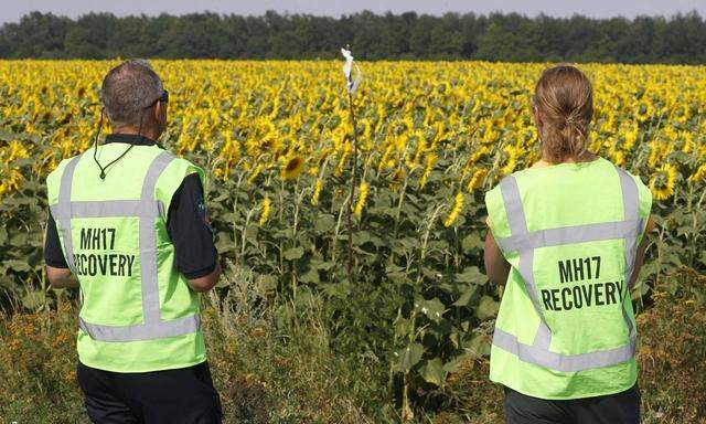 Forensic experts look at a makeshift marker denoting evidence during recovery work at the site of the downed Malaysian airliner near the village of Rozsypne
