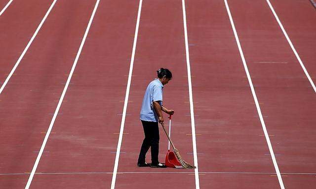A cleaner sweeps up rubbish lying on the athletics track at the Olympic Stadium, also known as the 'Bird's Nest', China in preperation for the upcoming World Atletics Championships