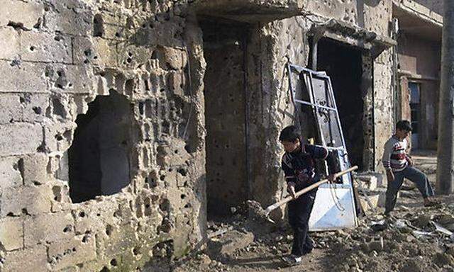 Boys remove debris from houses that residents say were damaged during a military crackdown on protest