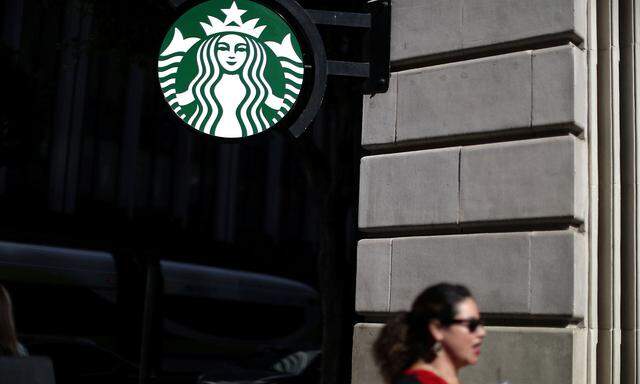 A woman holds a drink outside a Starbucks store in Los Angeles