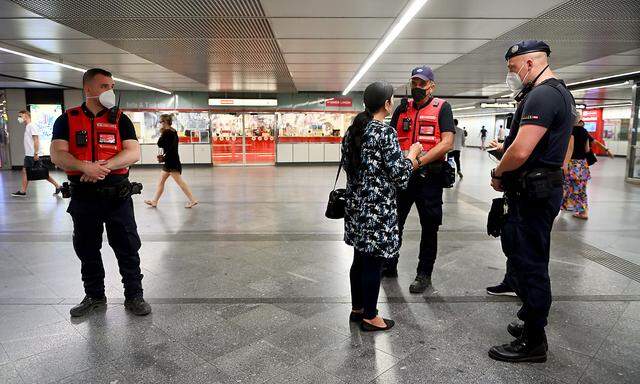 Eine Frau wird von Mitarbeitern der Wiener Linien und einem Polizisten angesprochen, weil sie im Stationsbereich keine FFP2-Maske trägt.