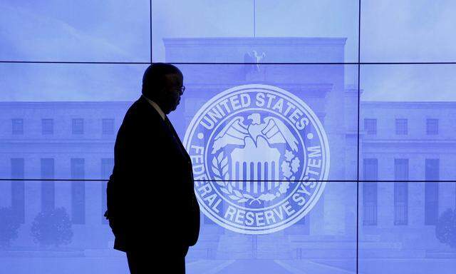 A guard walks in front of a Federal Reserve image before press conference in Washington