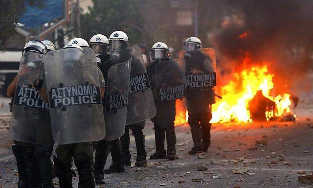 Riot police stand guard during clashes over stabbing of rapper in Athens