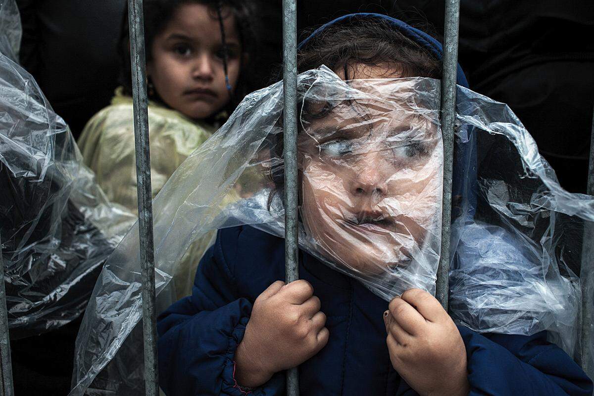 Matic Zorman, Slowenien, 2015, Waiting to Register Ein Mädchen unter einem Regencape wartet im Flüchtlingscamp in Preševo, Serbien, am 7. Oktober 2015 darauf, registriert zu werden.  