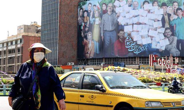Straßenszene aus Teheran, im Hintergrund ist ein Wahlplakat zu sehen. Ebrahim Raisi, der erzkonservative Chef der Justiz, stand schon vorher als Sieger fest.