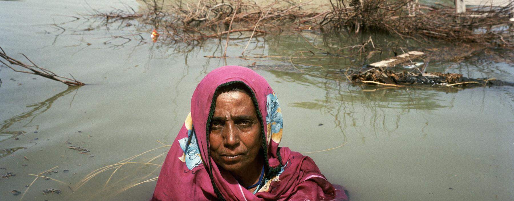 Eine Frau vor ihrem überschwemmten Haus in Pakistan.