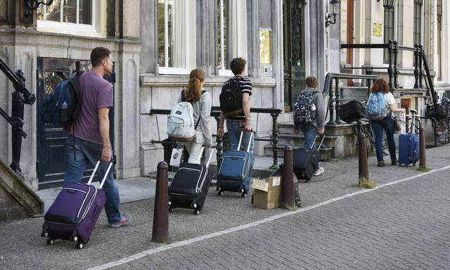 The Netherlands Amsterdam June 2018 Airbnb tourists with suitcases walk through the center of Am
