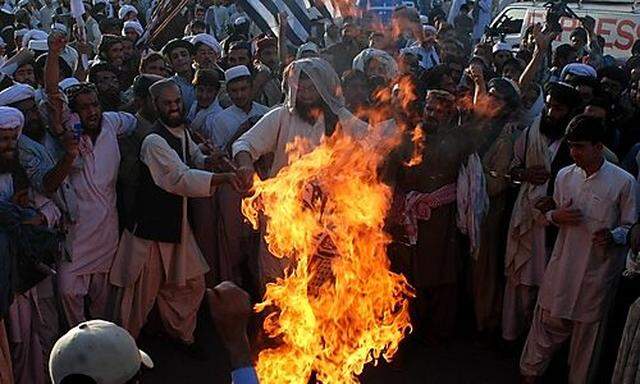 Angry supporters of Pakistani religious party Jamiat Ulema-e-Islam burn representation of the United 