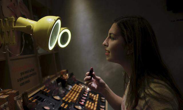 A woman checks lipstick applied on her lip, inside of a cosmetics shop in Sao Paulo