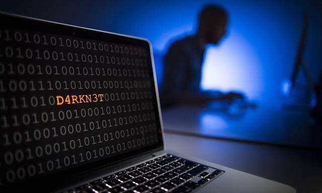 Illustration zum Thema Darknet Nahaufnahme eines Laptops mit Binaercode Im Hintergrund sitzt ein