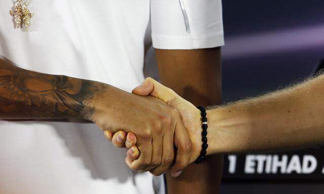 Mercedes Formula One driver Lewis Hamilton of Britain shakes hands with his team mate Nico Rosberg of Germany as they arrive for a press conference at the Yas Marina circuit before the start of the Abu Dhabi Grand Prix