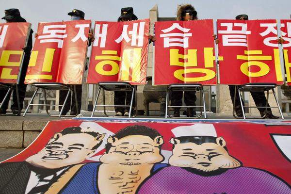 Weitere Überläufer hielten Plakate in die Höhe, die den toten Machthaber Kim Jong-il und dessen Familie als Schweine darstellen.