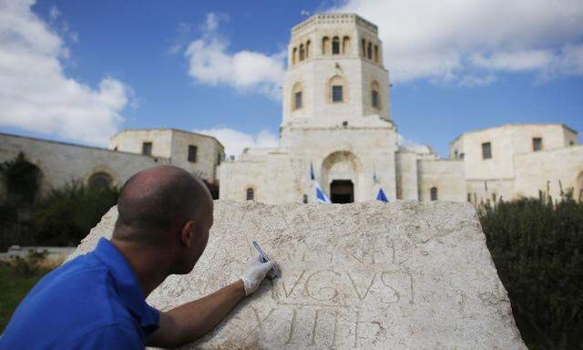 Shmulik Freireich, a worker for IAA, demonstrates the cleaning of an ancient Latin inscription engraved on a stone, displayed in Jerusalem