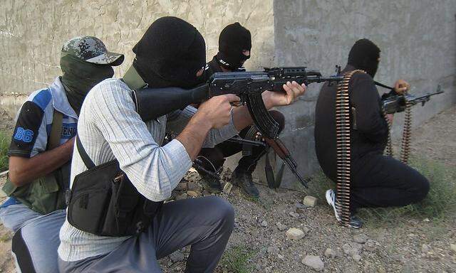 Masked Sunni gunmen hold their weapons as they take their positions during a patrol outside the city of Falluja